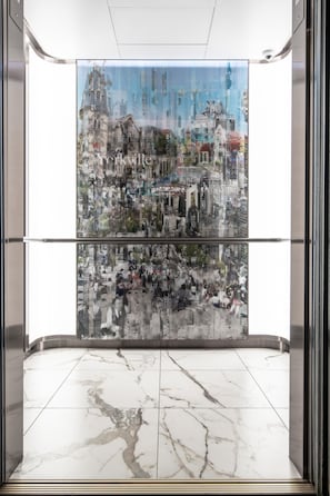 An elevator with a glass wall displaying a cityscape artwork. - Modern 1BR with Breathtaking Yorkville View (Toronto)