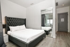 A modern bedroom with a large bed, a mirror, and a view of the city. - Modern 1BR with Breathtaking Yorkville View (Toronto)