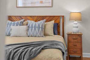 A bedroom with a bed, pillows, a bedside table with a lamp, and a wall-mounted picture. - Historic 4BR Cottage | Near Downtown and Beach (St. Augustine)