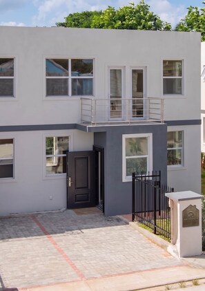 Ein zweistöckiges Gebäude mit Balkon, geschlossenem Eingangstor und Auffahrt.