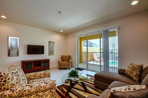 A living room with a sofa, armchair, and a glass coffee table. - 3BR Townhouse Near Disney Private Pool (Clermont)