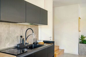 A modern kitchen with a black countertop, stainless steel sink, and grey cabinets. - Family villa in the countryside of Oriago (Mira)