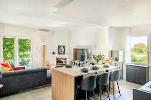 A modern kitchen with a central island, dining area with chairs, a sofa, and a fire extinguisher. - Family villa in the countryside of Oriago (Mira)