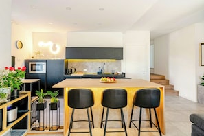 A modern kitchen with a central island, bar stools, and a dining table. - Family villa in the countryside of Oriago (Mira)