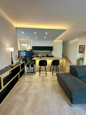A modern kitchen with a central island, bar stools, and a dining area with a sofa. - Family villa in the countryside of Oriago (Mira)