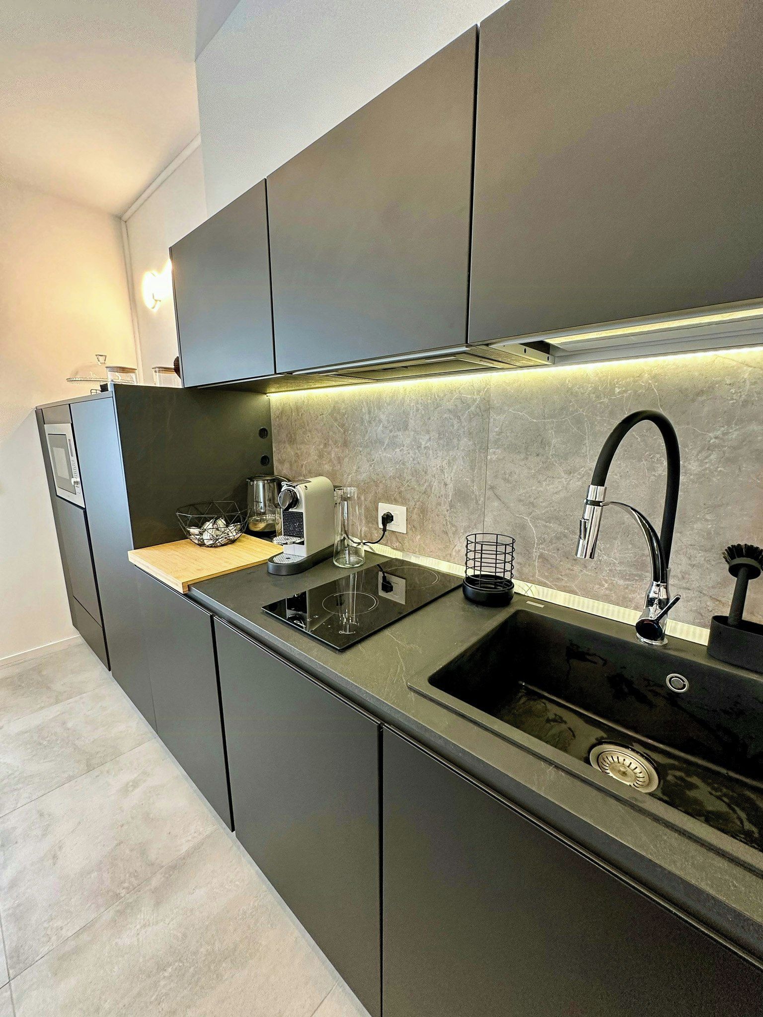Una cucina moderna con piano cottura integrato, lavandino e macchina per il caffè.