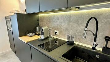 Una cucina moderna con piano cottura integrato, lavandino e macchina per il caffè.