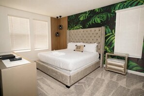 A bedroom with a large bed, a bedside table, a wall-mounted lamp, and a window with blinds. - 6BR Home w/ Pool, Theater & Game Room (Kissimmee)