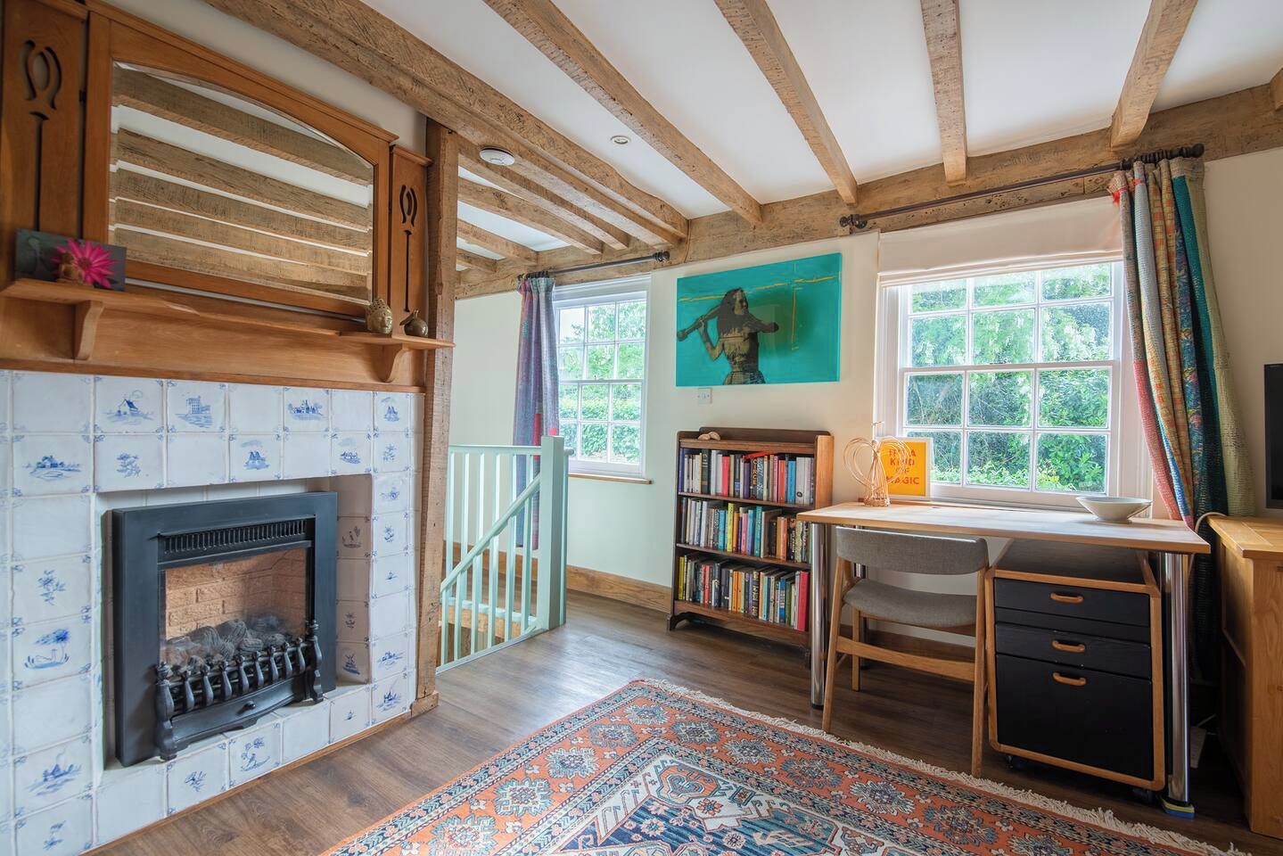 A room with a fireplace, bookshelves, a desk, and a view through a window.