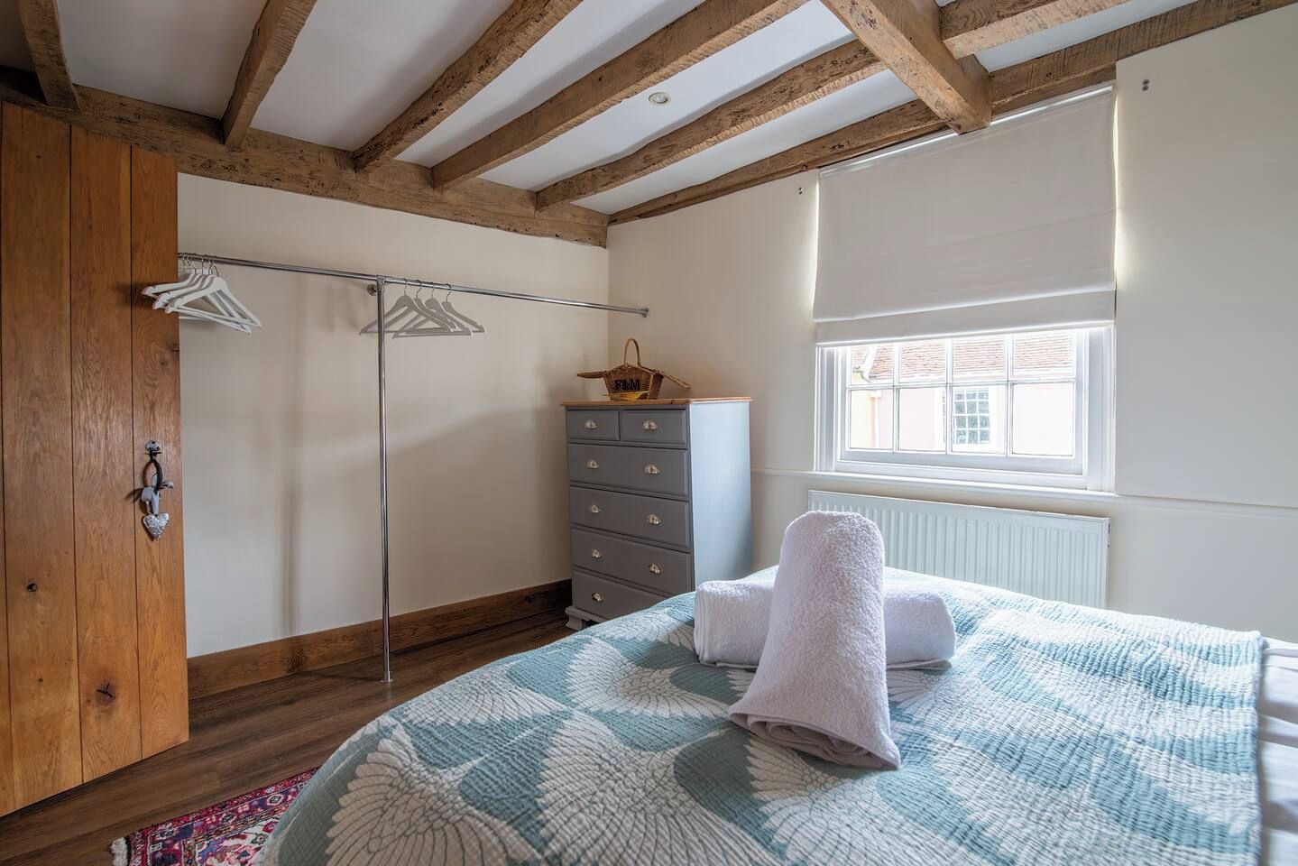 A bedroom with a bed, a dresser, a wardrobe, and a window.