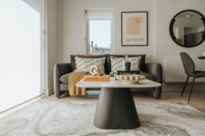 Ein modernes Wohnzimmer mit einer Couch, einem Couchtisch, einem gerahmten Kunstwerk und Blick auf die Stadt.