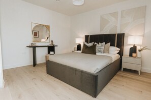 Ein Schlafzimmer mit einem großen Bett, Nachttischen, einem Spiegel und Wandbildern.
