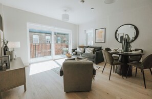 Ein modernes Wohnzimmer mit einer Couch, Hocker und einem Essbereich mit Stühlen und einem Tisch.