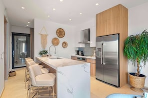 A modern kitchen with a central island, stainless steel appliances, and a seating area with bar stools. - Top Floor Beach Condo|Near Eagle Beach|Pool&Jacuzzi (Pos Abou)