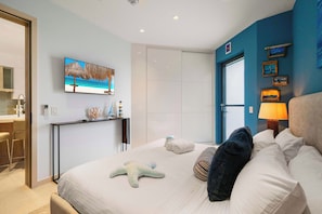 A hotel room with a bed, a starfish decoration, a TV on the wall, and a view of the sea. - Top Floor Beach Condo|Near Eagle Beach|Pool&Jacuzzi (Pos Abou)