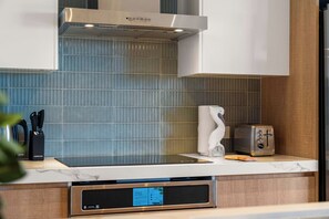 Una cocina moderna con horno empotrado, tostadora y un bloque de cuchillos sobre la encimera.