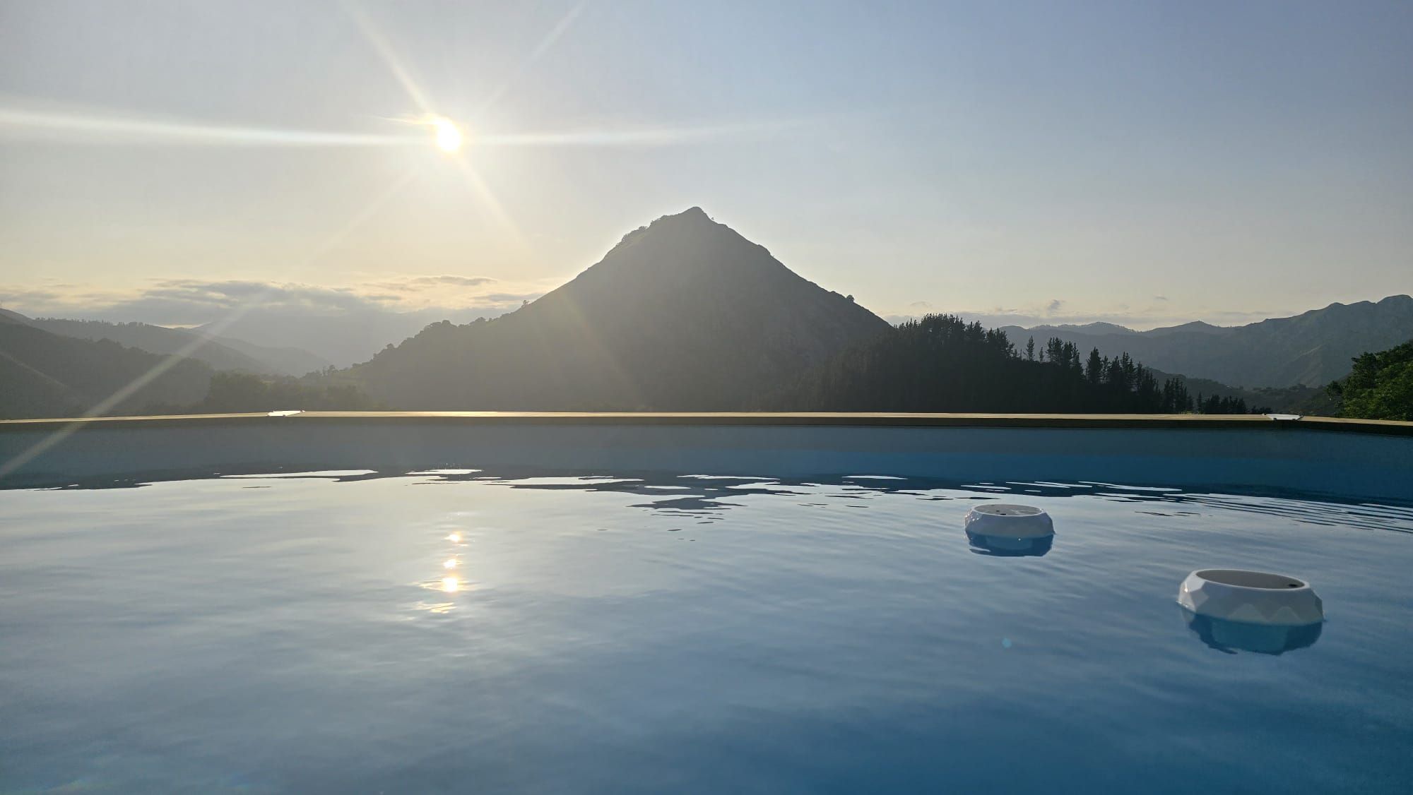 Ein ruhiger Pool im Freien mit Blick auf Berge, zwei Schalen und einem klaren Himmel.