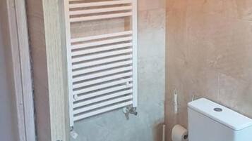 Un baño con inodoro, toallero y zona de ducha.
