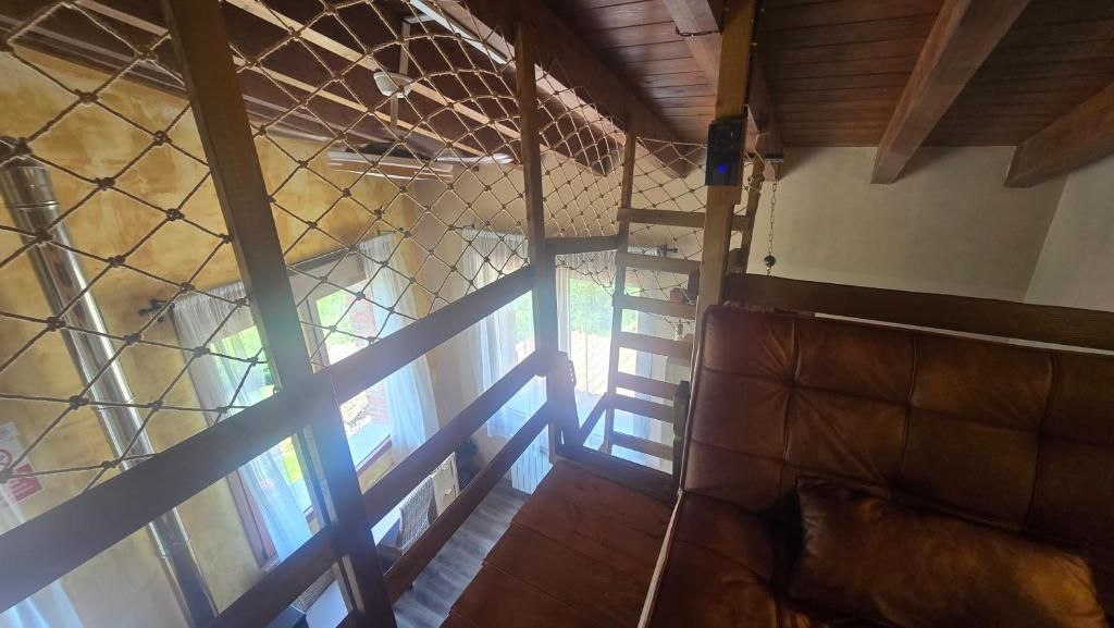 Una habitación con techo de madera, una zona de estar con cojines y vistas a través de una ventana con reja de metal.
