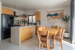 Eine moderne Küche mit einer zentralen Kochinsel, Holzschränken und einem Essbereich mit Tisch und Stühlen.