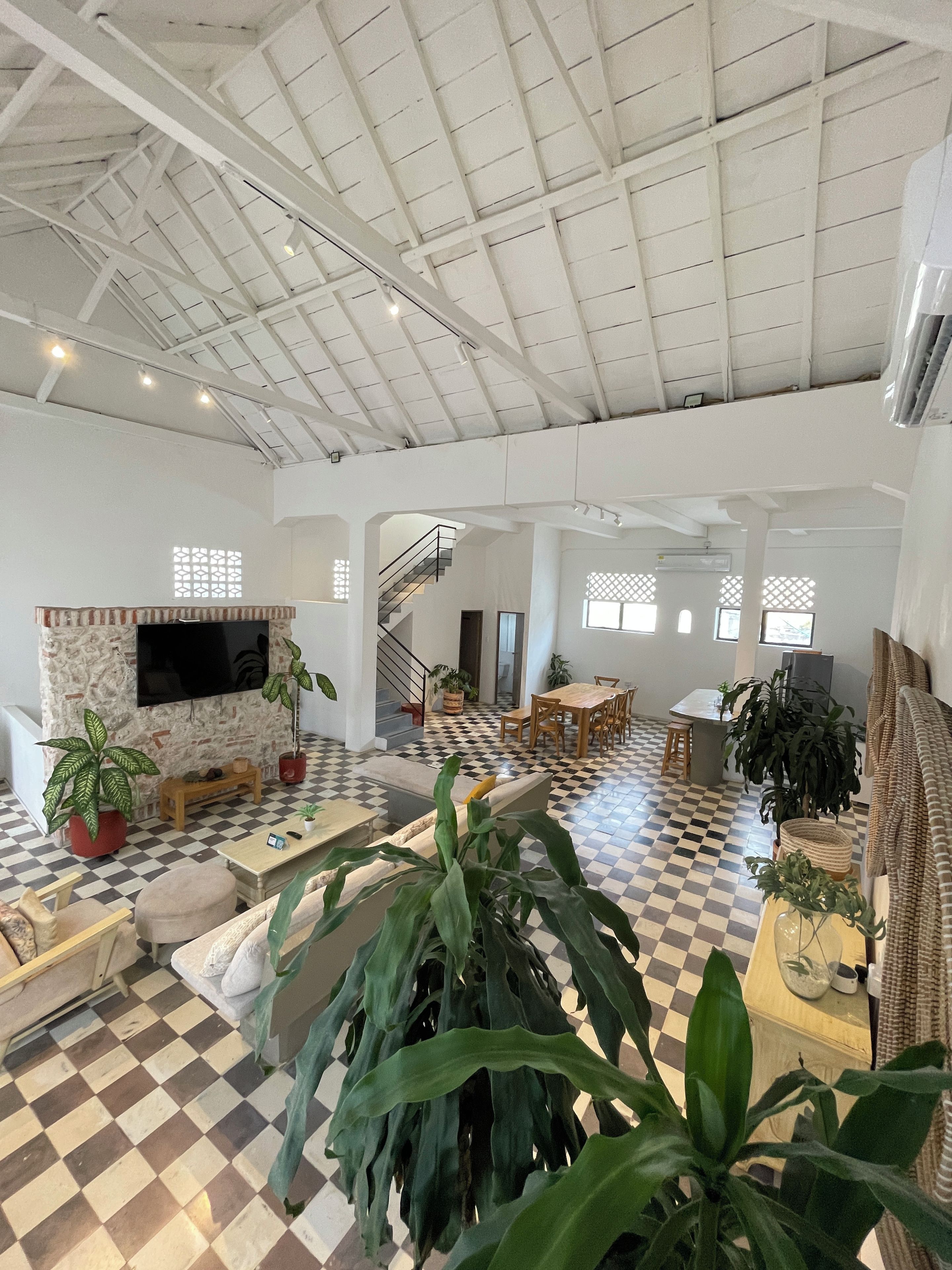 A spacious living area with a high ceiling, checkered flooring, and a fireplace.