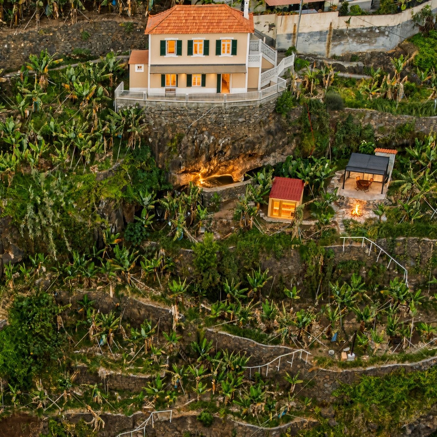 Ein zweistöckiges Gebäude mit Balkon, umgeben von üppiger Vegetation und einer Steinmauer.