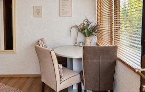 A dining area with a round table, two chairs, a vase with flowers, and two inspirational signs on the wall.