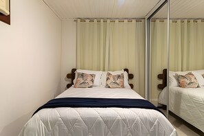 A bedroom with a bed, a mirror, and a window with curtains. - Casa 1 Porto Seguro 6 Quartos e Piscina (Porto Seguro)