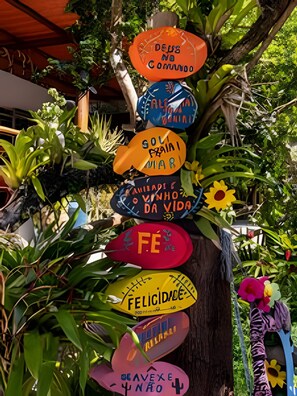 A tree with colorful signs attached to it, surrounded by lush greenery. - Casa 1 Porto Seguro 6 Quartos e Piscina (Porto Seguro)