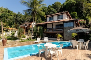 A two-story house with a swimming pool, outdoor seating, and lush greenery. - Casa 1 Porto Seguro 6 Quartos e Piscina (Porto Seguro)