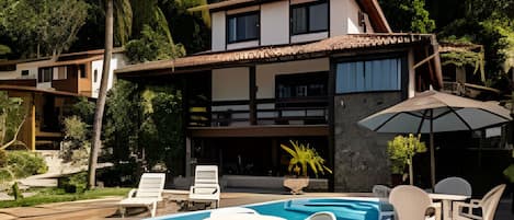 A modern house with a swimming pool, outdoor furniture, and lush greenery.