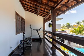 A balcony with exercise equipment, a view of the surrounding area, and a pool. - Casa 1 Porto Seguro 6 Quartos e Piscina (Porto Seguro)