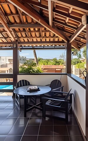 A covered outdoor seating area with a table and chairs, a view of the pool, and a tiled floor. - Casa 1 Porto Seguro 6 Quartos e Piscina (Porto Seguro)