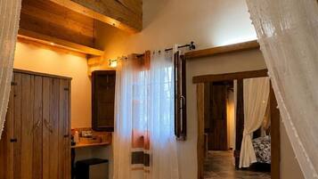 Ein Zimmer mit Holzboden, einem Bett mit gemustertem Überwurf und einem Badezimmer mit Holzkabinent.