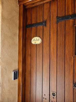 A wooden door with a brass handle, a keypad lock, and a sign with the name 'ALBA'.