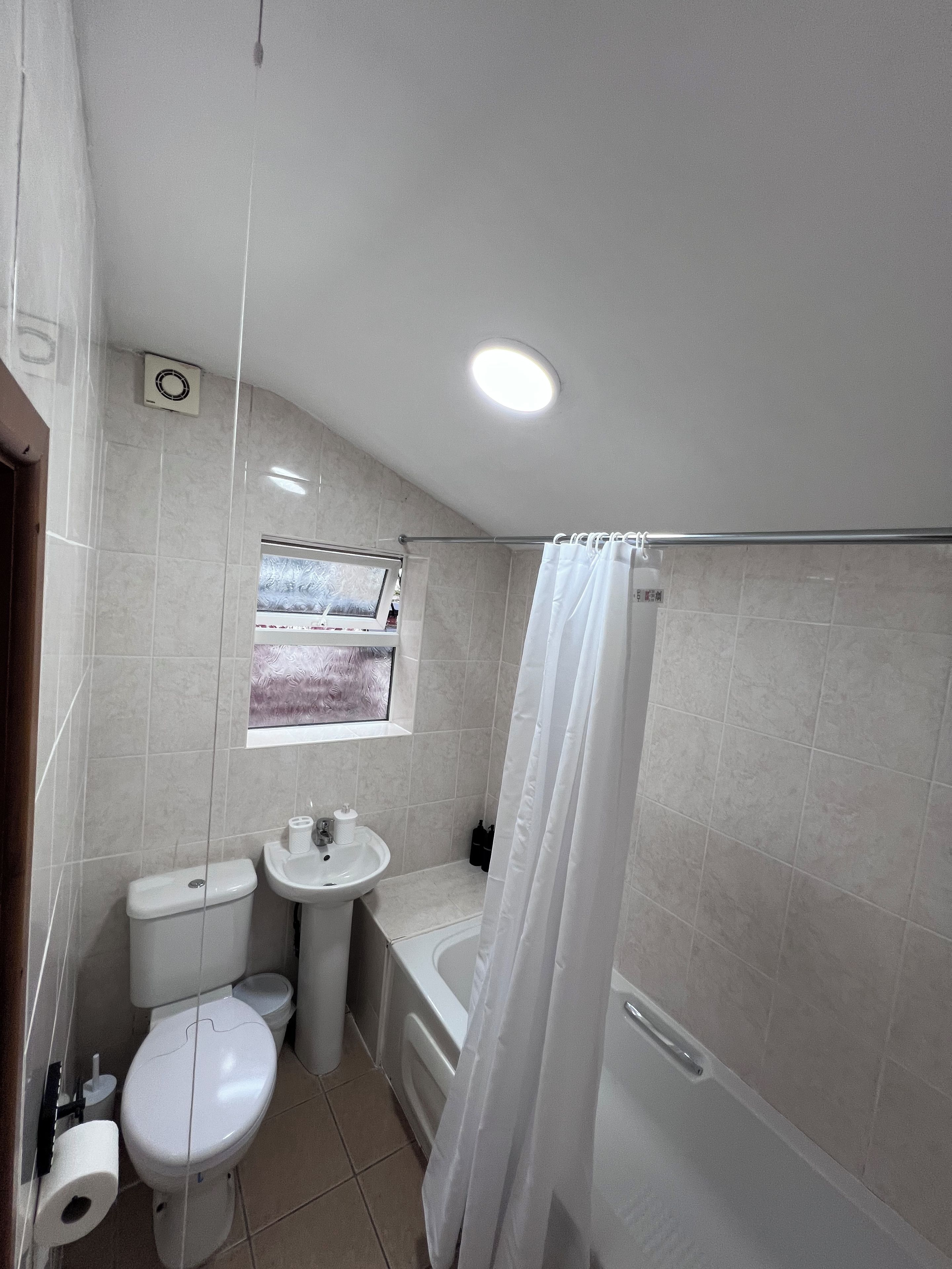 A bathroom with a toilet, sink, bathtub, and a window with a view.