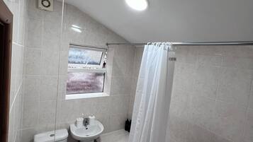 A bathroom with a toilet, sink, bathtub, and a window with a view.