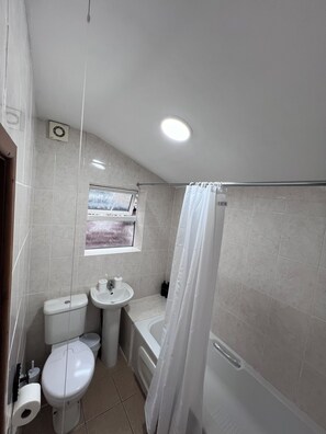 A bathroom with a toilet, sink, bathtub, and a window with a view. - 6 minutes drive from Coventry city centre!
For families,contractors & travelers (Coventry)