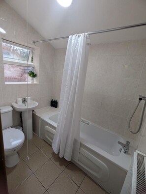 A bathroom with a toilet, sink, bathtub, and shower curtain. - 6 minutes drive from Coventry city centre!
For families,contractors & travelers (Coventry)