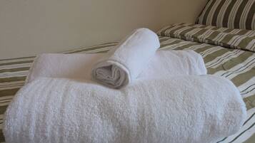 Una cama con una colcha a rayas y dos toallas blancas enrolladas.