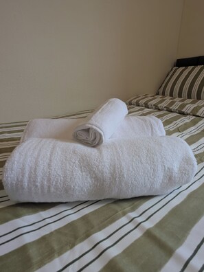 A bed with a striped bedspread and two rolled white towels. - 6 minutes drive from Coventry city centre!
For families,contractors & travelers (Coventry)