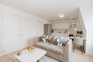 A modern living space with a sofa, a dining table, and a kitchen area. - Stonehouse Stays · Luxury Clapham 1-Bed. (London)
