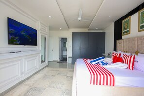 A hotel room with a large bed, a flat-screen TV, a wardrobe, and a bathroom visible through an open door. - 3-bedroom ocean-view apartment, where modern comfort meets breathtaking views. (Mombasa)