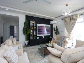 A modern living room with a flat-screen TV, comfortable sofas, a glass coffee table, and decorative plants. - 3-bedroom ocean-view apartment, where modern comfort meets breathtaking views. (Mombasa)