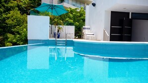 Una piscina con azulejos azules cristalinos, una pared blanca y una puerta.