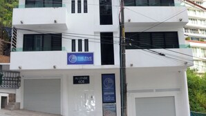 Un edificio moderno de varios pisos con un letrero que dice 'The Five Downtown Puerto Vallarta' y un número de contacto.