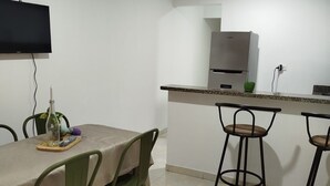 Cocina compacta con microondas integrado, un refrigerador pequeño y una barra con taburetes.