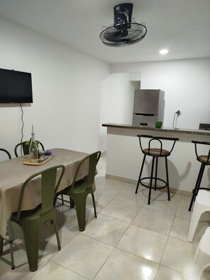 A compact kitchen with a built-in microwave, a small refrigerator, and a bar area with stools. - Vrbo Property (Cartagena de Indias)