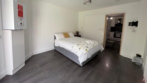 A bedroom with a bed, a heater, and a door leading to a bathroom. - Apartment Sleeps 7 With Patio (Hayes)