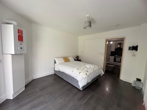 Une chambre à coucher comprenant un lit, un radiateur et une porte donnant sur une salle de bain.